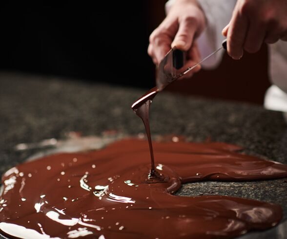 Chocolatier travaillant le chocolat tempéré sur un marbre