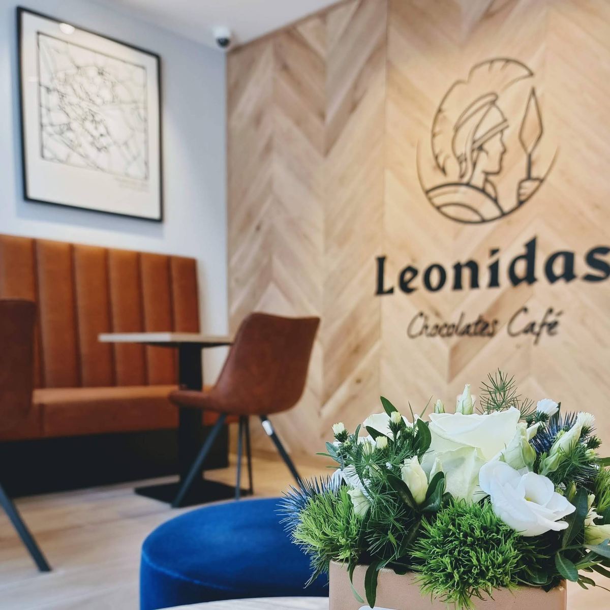 Intérieur de la boutique Leonidas Hazebrouck : mur en bois clair avec le logo Chocolates Café et fauteuils