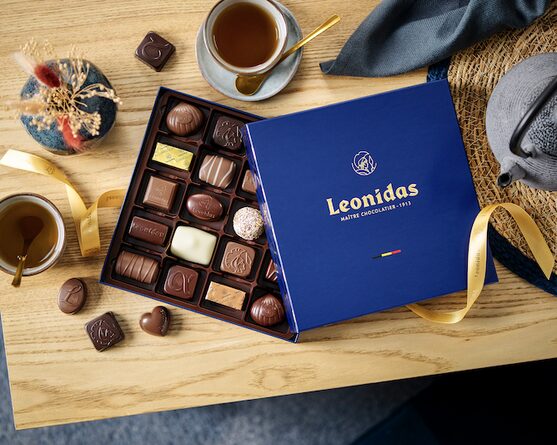 Coffret bleu Leonidas ouvert sur une table, garni de pralines assorties